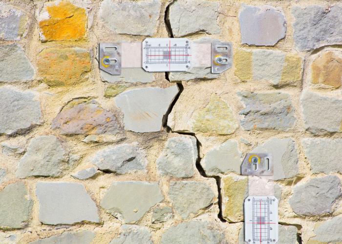 Crack gauges on stone wall during foundation inspection in Muskegon